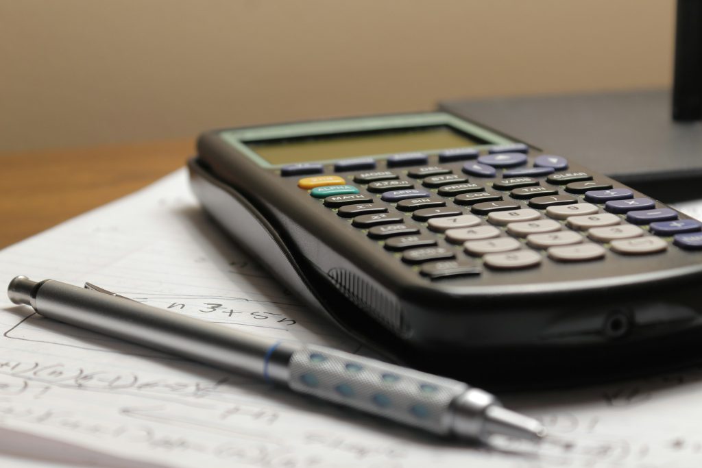 Calculadora negra y portaminas sobre una hoja de cuaderno con operaciones escritas a mano